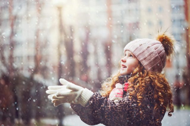 防寒具を身にまとった雪の中の少女